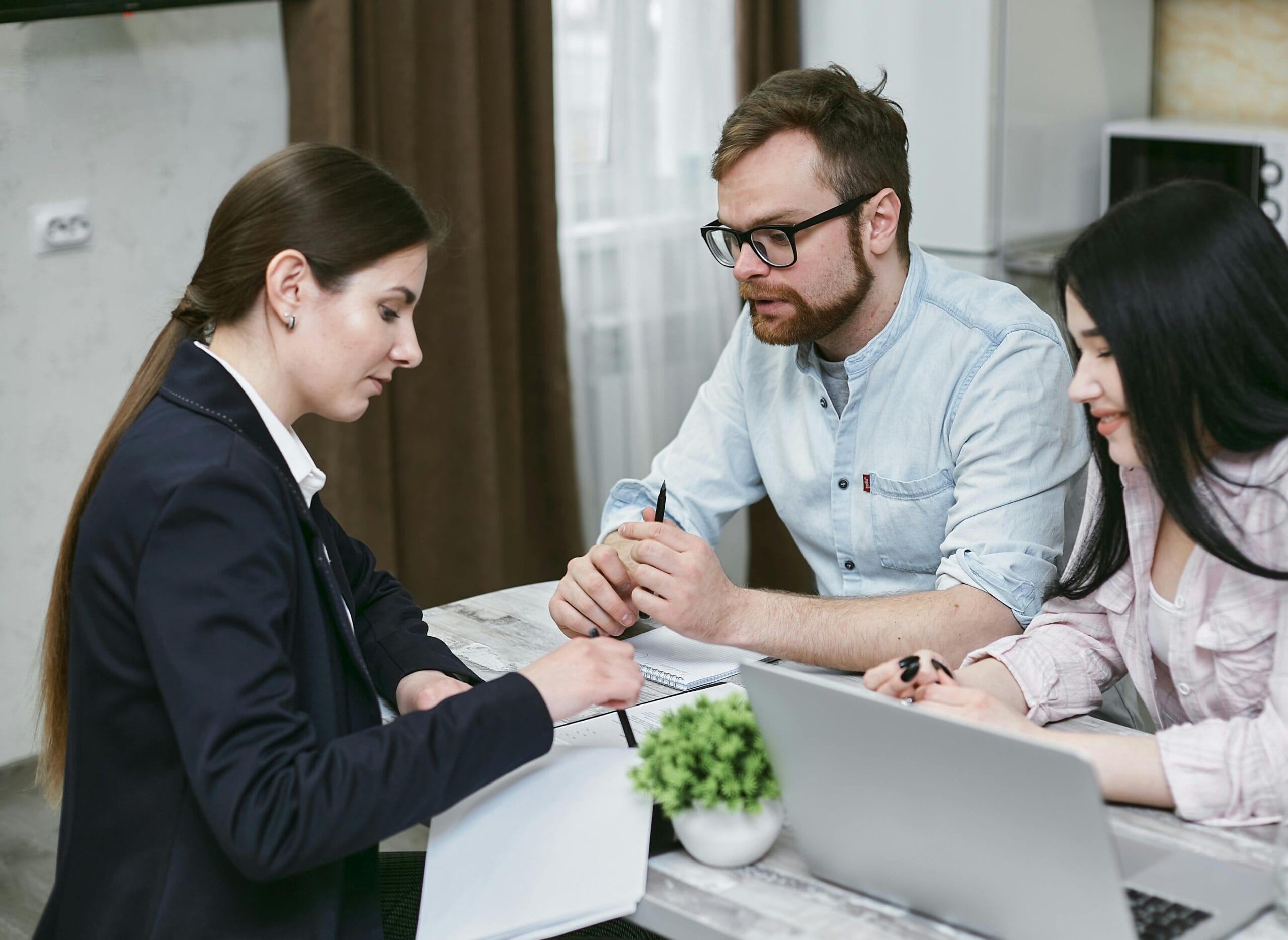 An advisor with two clients looking at papers on a desk.