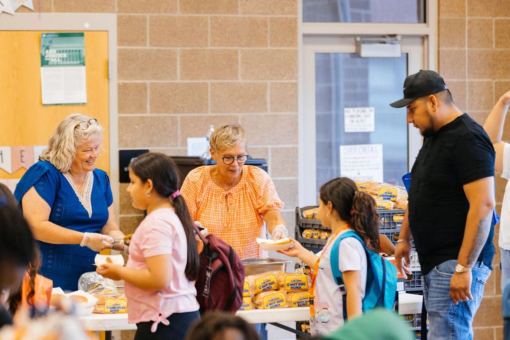 People in a gym getting served lunch.