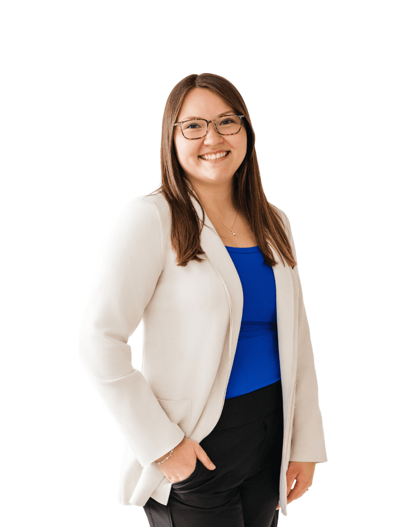 Woman in a cream color blazer and glasses standing in front of a white background.