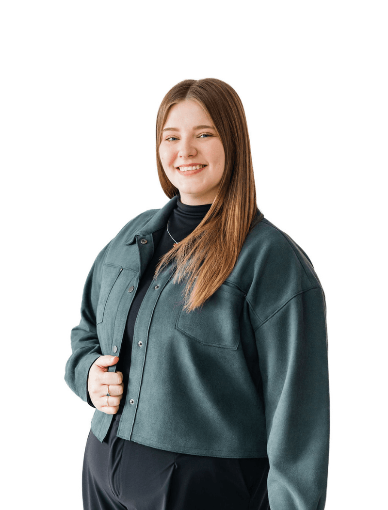 Staff member standing in front of a white background in a green jacket.