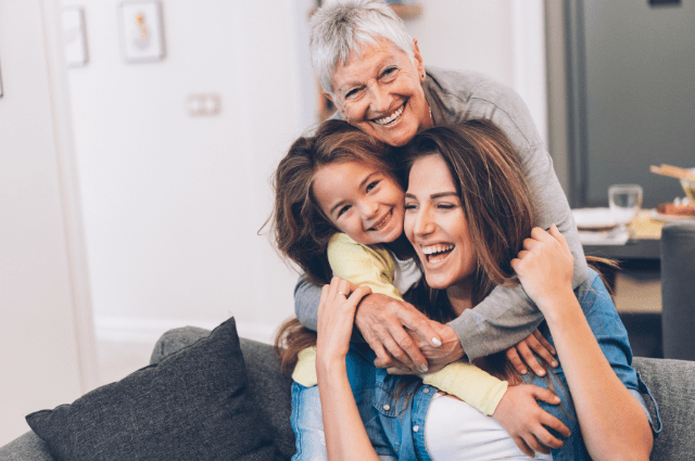 Three generations of women hugging and smiling.