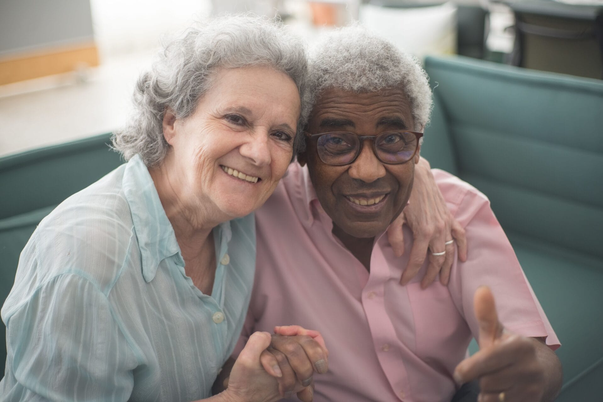An older man and woman smiling and holding hands.
