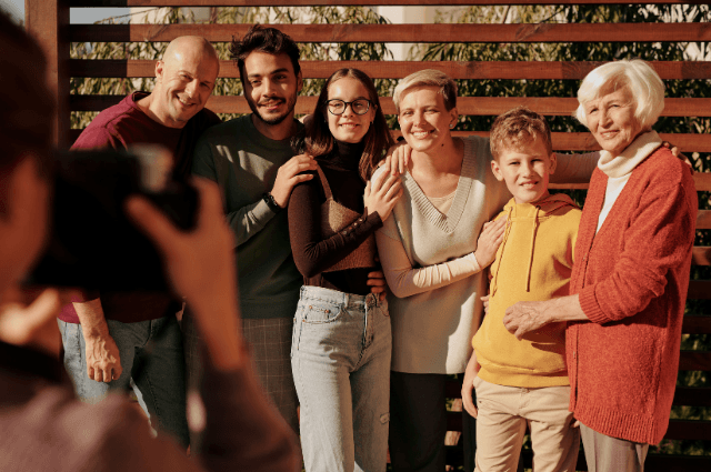 A family standing in front of a fence with their hands on each other's shoulders, posing for a picture.